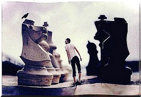 A man surrounded by giant chess pieces