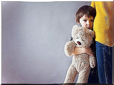 Sad boy seeks comfort from his mother and holds a teddy bear