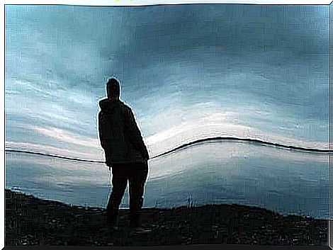 Man looking out over a sea at sunset.