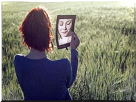 Woman standing in meadow and looking in the mirror