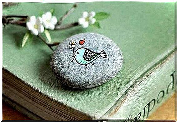 A bird carrying a flower, painted on a rock.