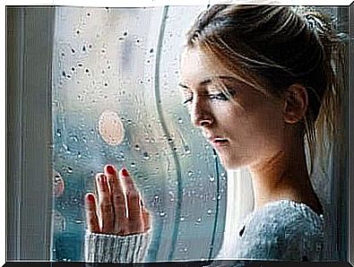 Sad woman with her hand on a window