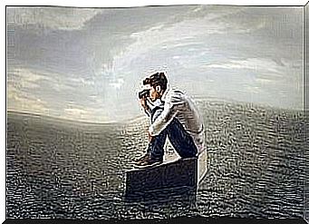 Man sitting on suitcase at sea and looking in binoculars