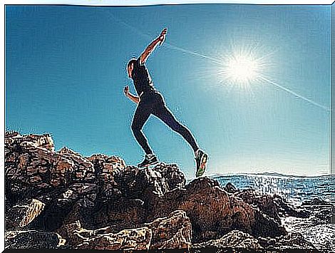 a runner jumps up on a hill by the water