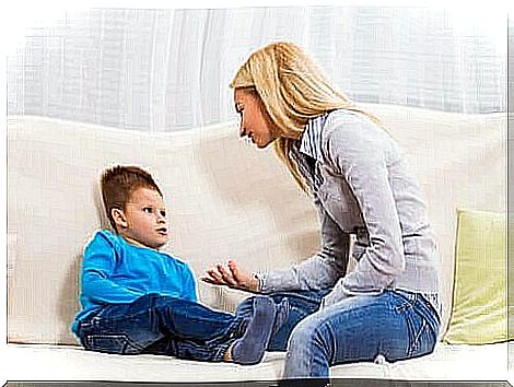 A mother sitting on the couch with her son and explaining something to him.